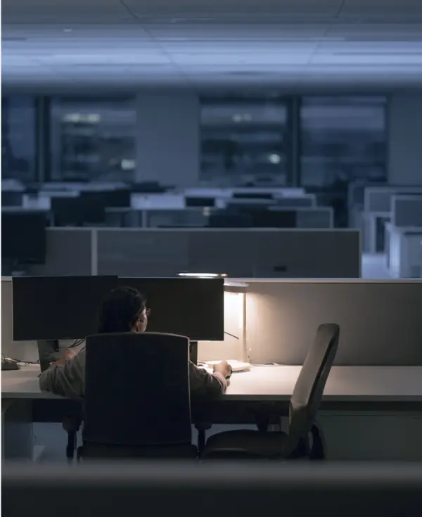 An enterprise engineering floor after hours, one desk still lit